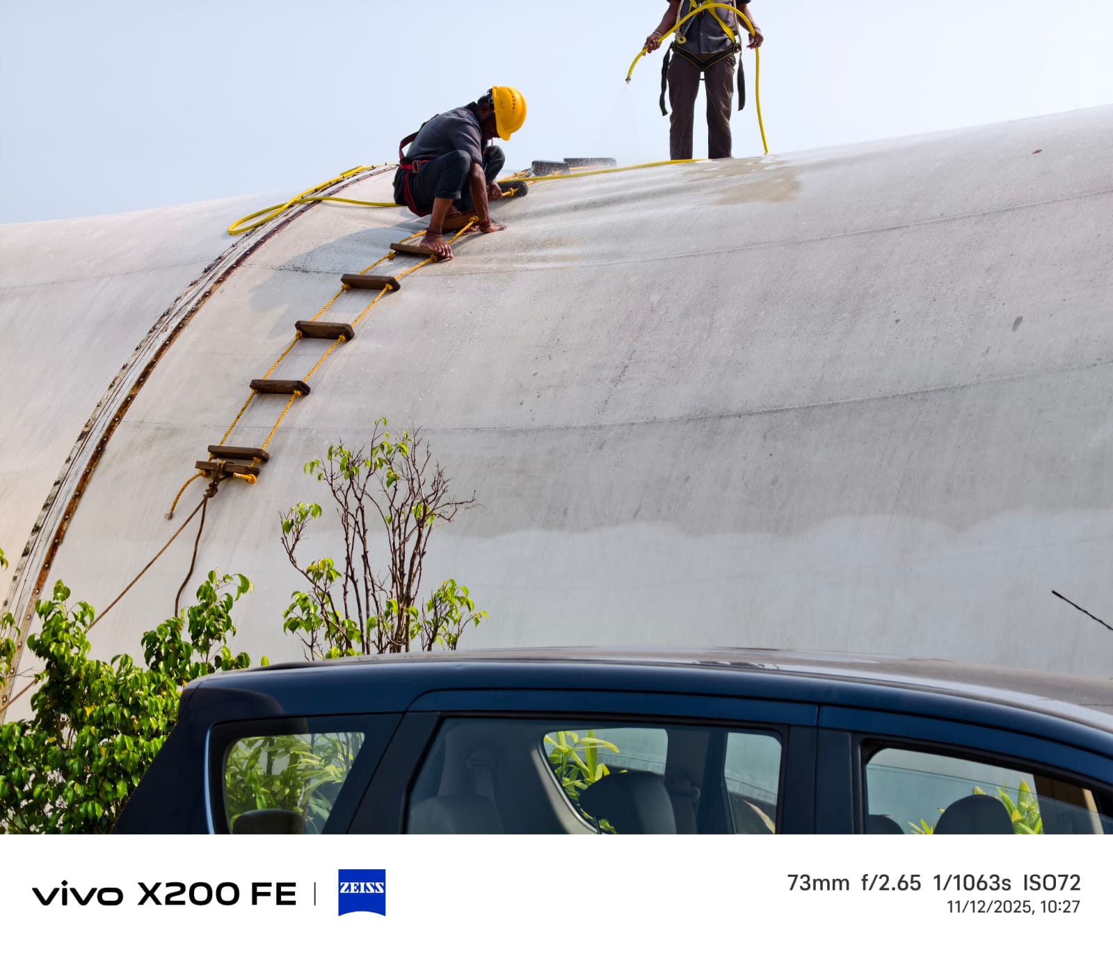 Crew in safety harnesses cleaning a large overhead water tank in Goa